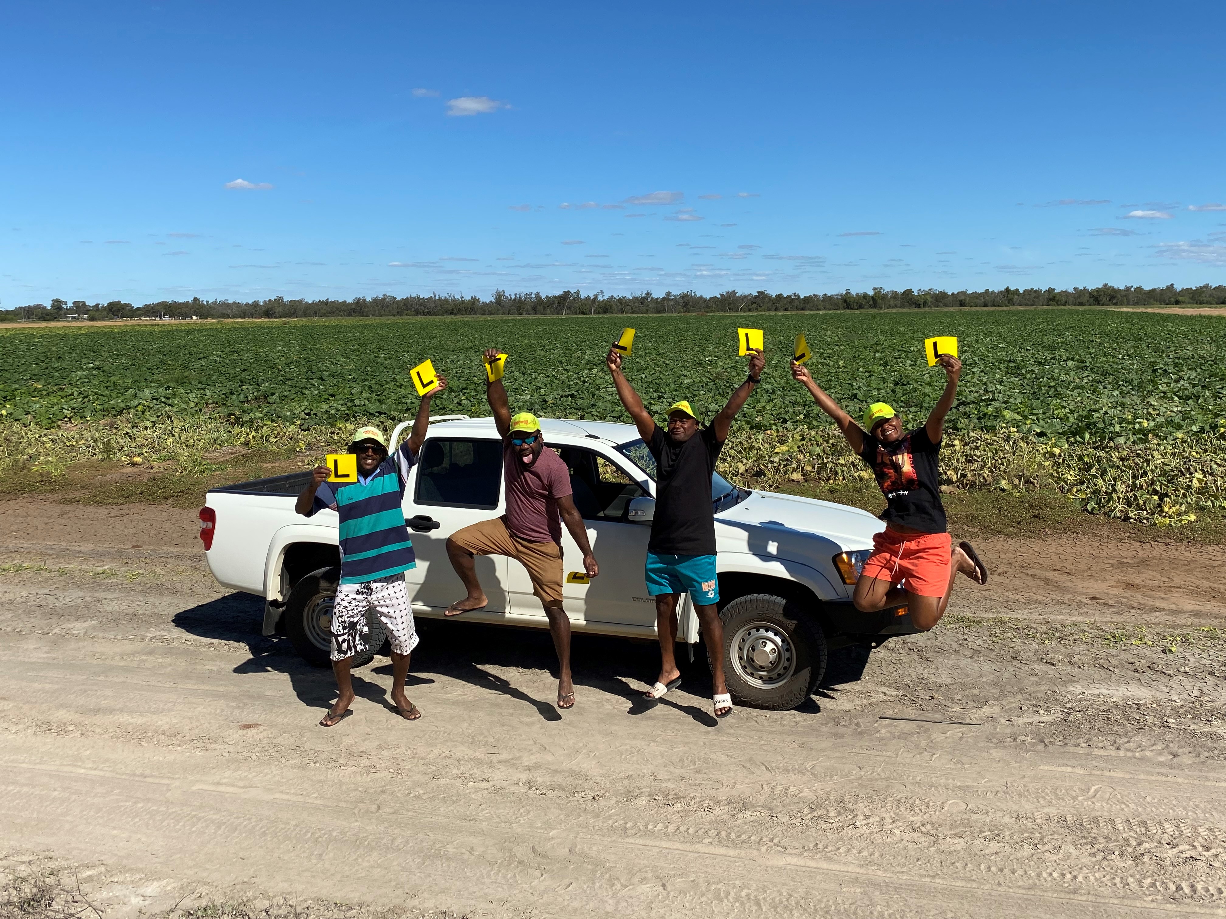 4 Ni-Vanuatu people jump into the air and celebrate by holding up L plates.