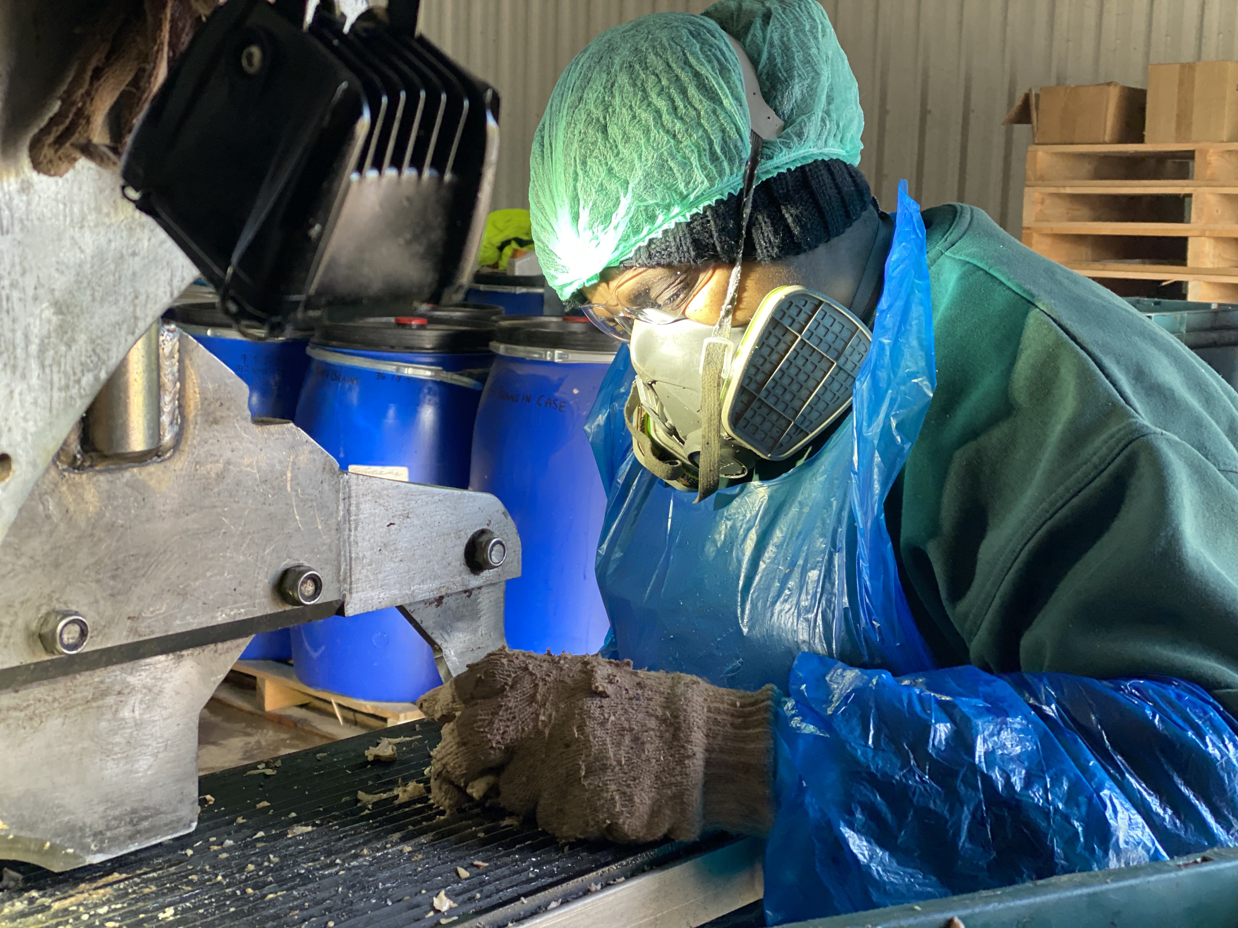 A person sits at a machine wearing PPE