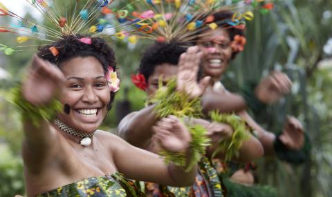 Fijian women in traditional dress dancing and smiling and looking into the camera