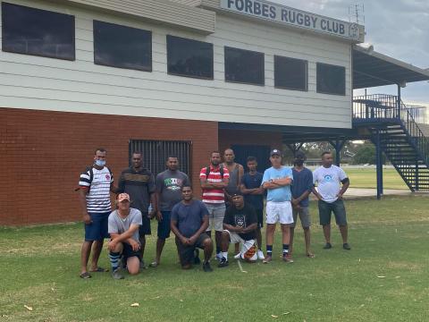 A group of Fijian men stand in front of the clubhouse to the Forbes Rugby Union club.