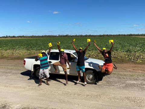4 Ni-Vanuatu people jump into the air and celebrate by holding up L plates.