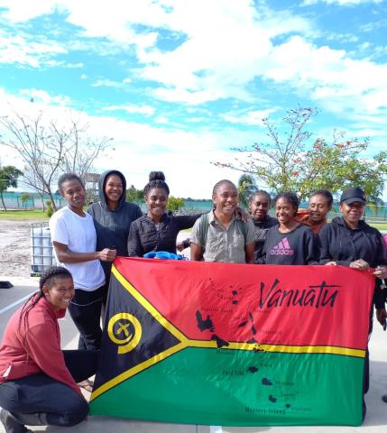 A group of ni-Vanuatu women stand with a Vanuatu flag.