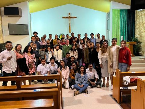 A group of Timorese people stand in a church around a bishop.