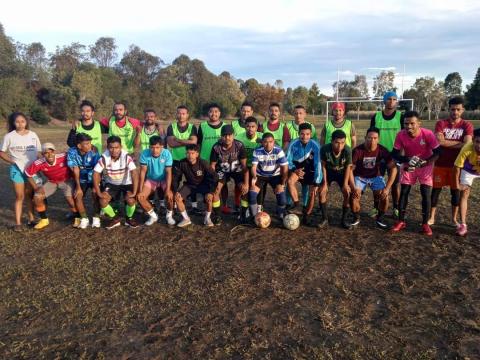 A large group of Timorese men play soccer.