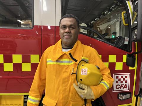 Fijian worker Josateki stands by firetruck smiling