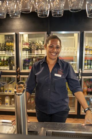 A woman in a uniform stands at a bar
