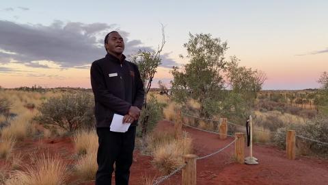 A man stands in the desert delivering a speech
