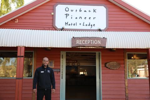 A man stands smiling in front of a hotel reception