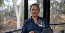 A woman standing in a restaurant cleaning a wine glass